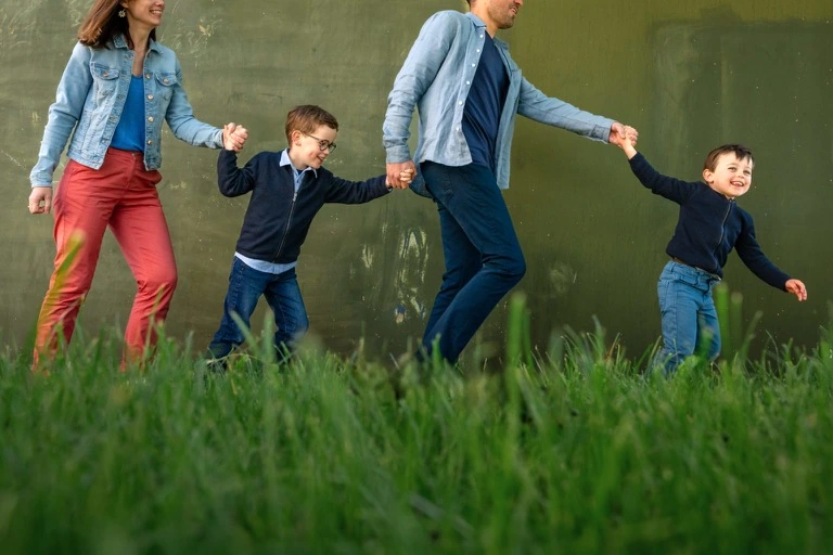 Une famille court main dans la main dans les hautes herbes