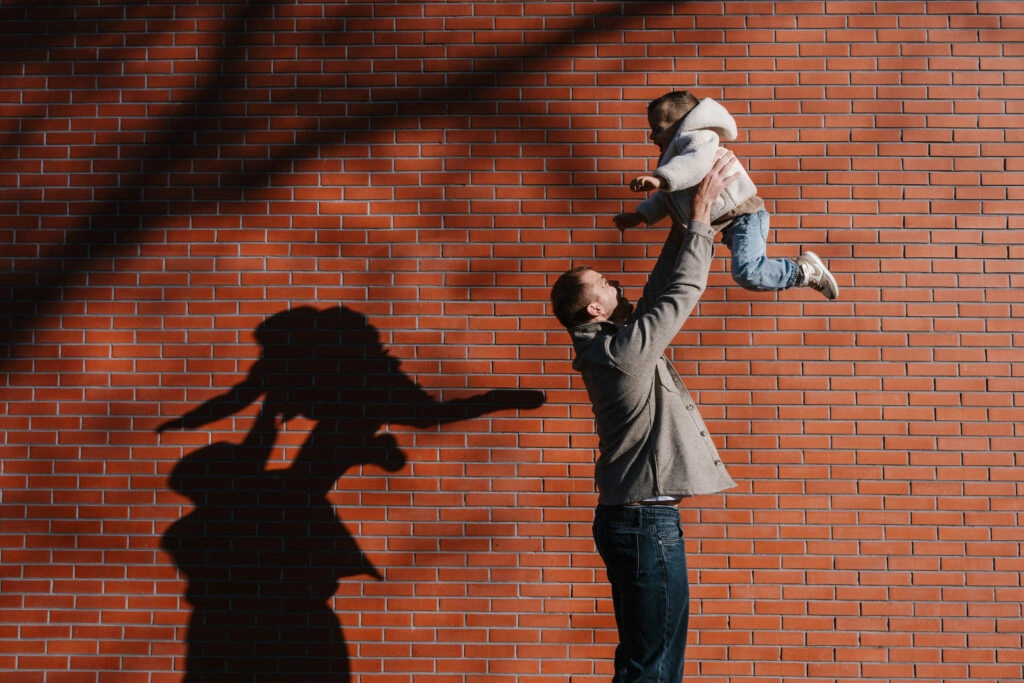 Un père soulève son enfant à bout de bras pendant une séance photo en famille.