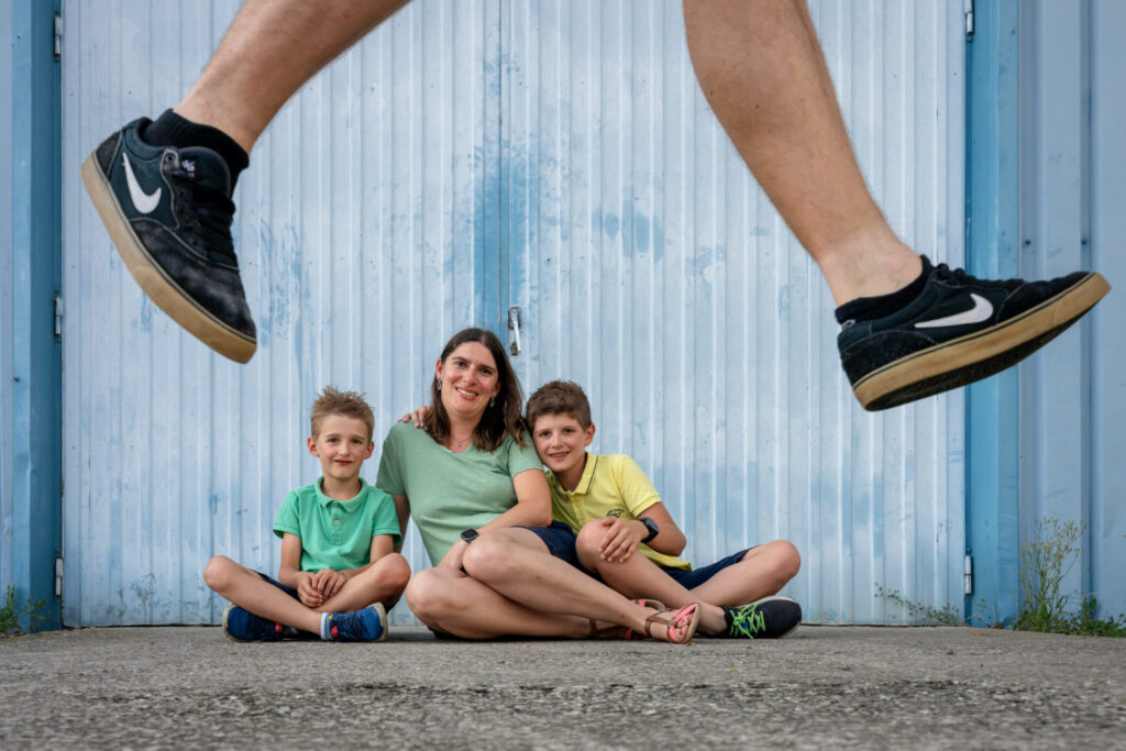 Une femme et deux enfants assis, avec les jambes d’un sauteur au premier plan