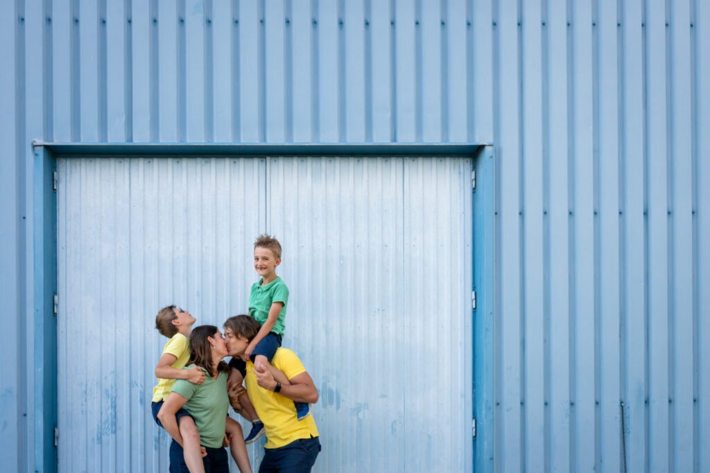 Une famille pose en s’empilant devant une grande porte bleue