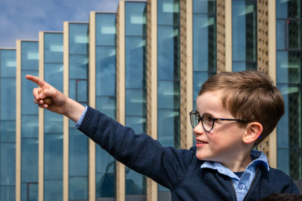 Un garçon en lunettes pointe du doigt en souriant