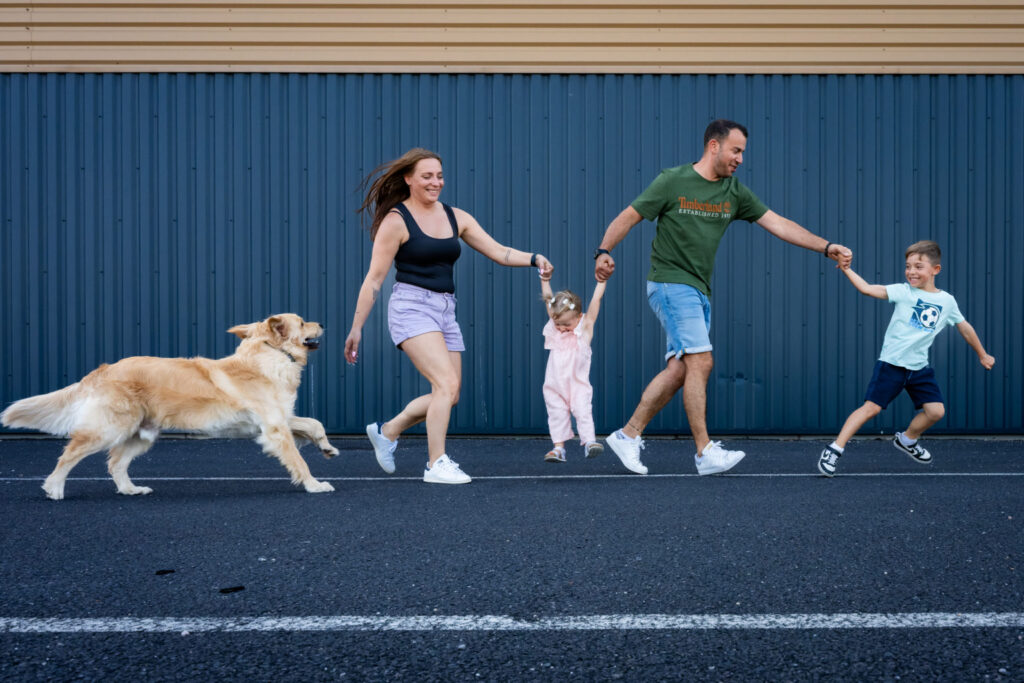 Une famille marche avec son chien devant une façade bleue