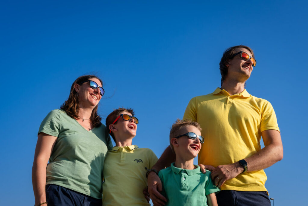 Une famille en lunettes de soleil regarde au loin sous un ciel bleu
