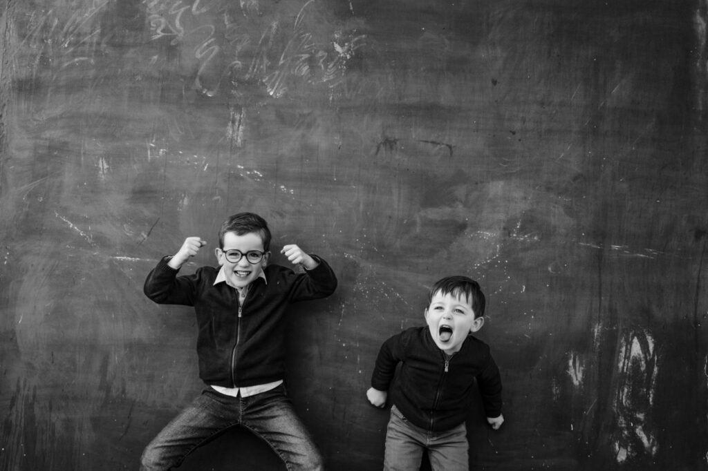 Deux garçons font des grimaces devant un mur, en noir et blanc