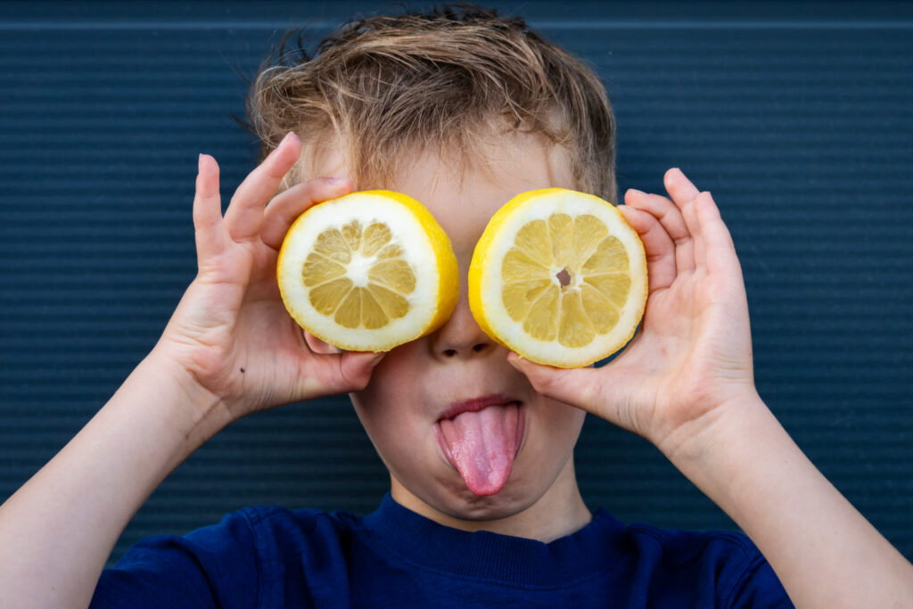 Un garçon tire la langue avec deux rondelles de citron devant les yeux