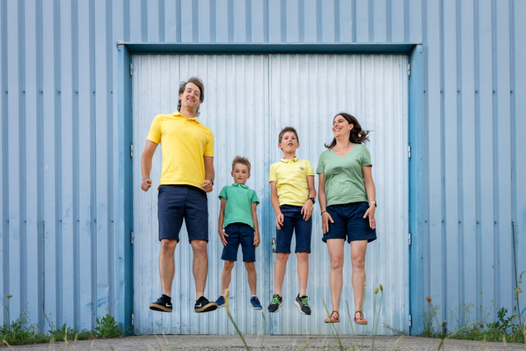 Une famille saute ensemble devant une porte bleue