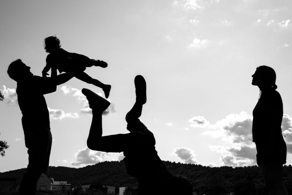 Une famille joue en silhouettes, un enfant soulevé dans les airs