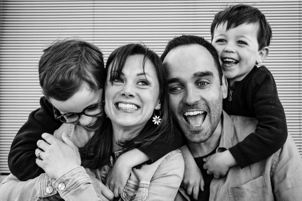 Une famille se serre dans les bras en riant, en noir et blanc