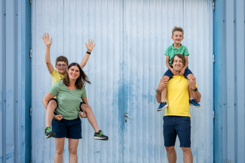 Des parents portent leurs enfants sur les épaules devant une porte bleue