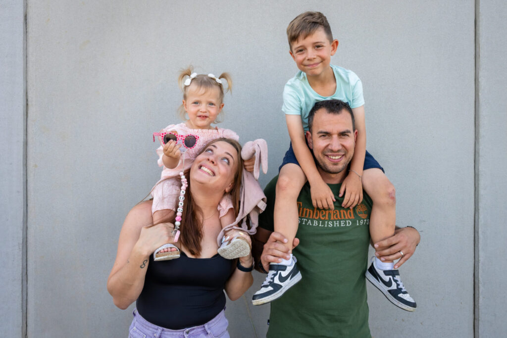 Deux enfants sur les épaules de leurs parents pendant une séance famille