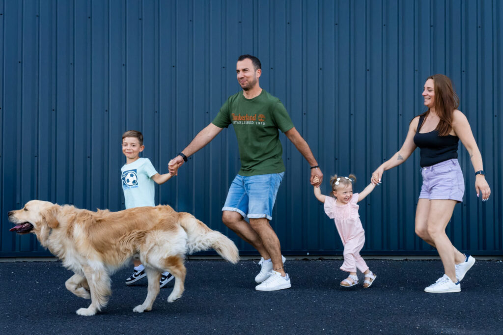 Une famille se tient la main en marchant avec son chien