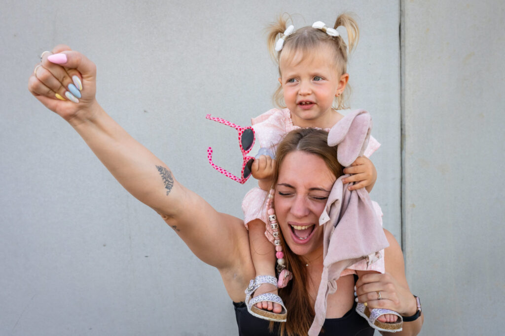 Une petite fille sur les épaules de sa mère pendant un jeu de bulles