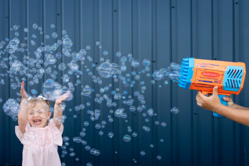 Une petite fille lève les mains vers une pluie de bulles