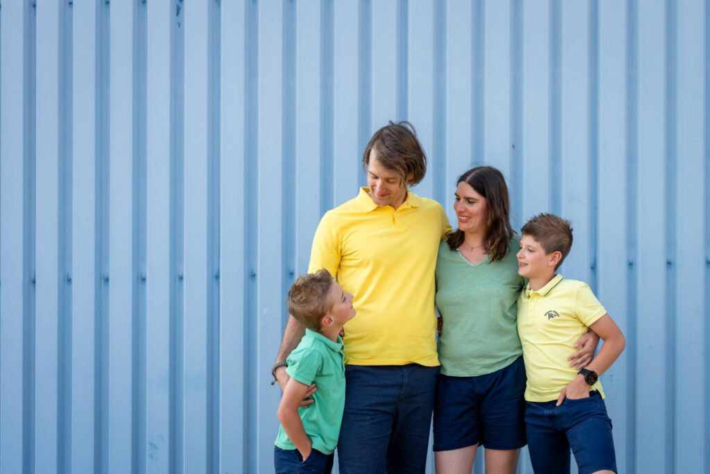 Une famille se regarde devant une façade bleue