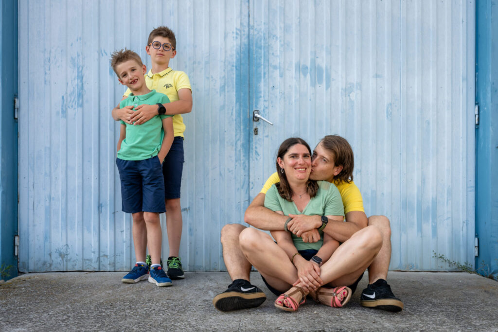 Une famille prend des poses amusantes, debout et assise devant une porte bleue