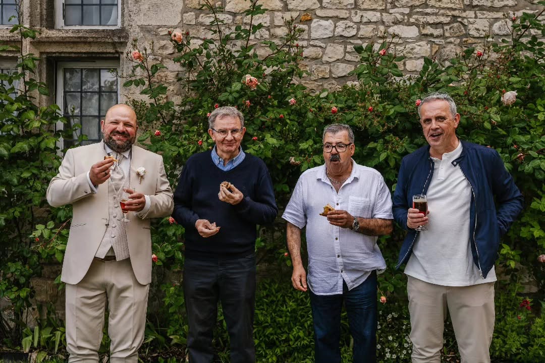 Patrice et trois invités partagent un moment au cocktail devant les pierres et les rosiers du château.