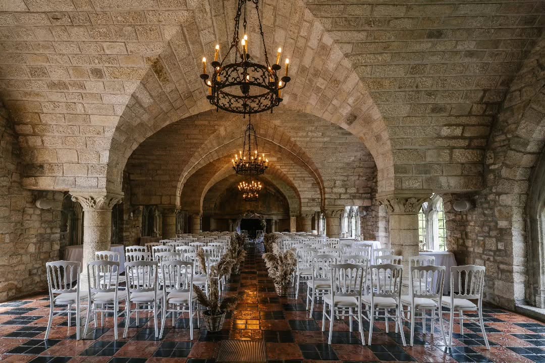 La salle voûtée du Château de Hattonchâtel, aménagée avec des rangées de chaises blanches pour le mariage.
