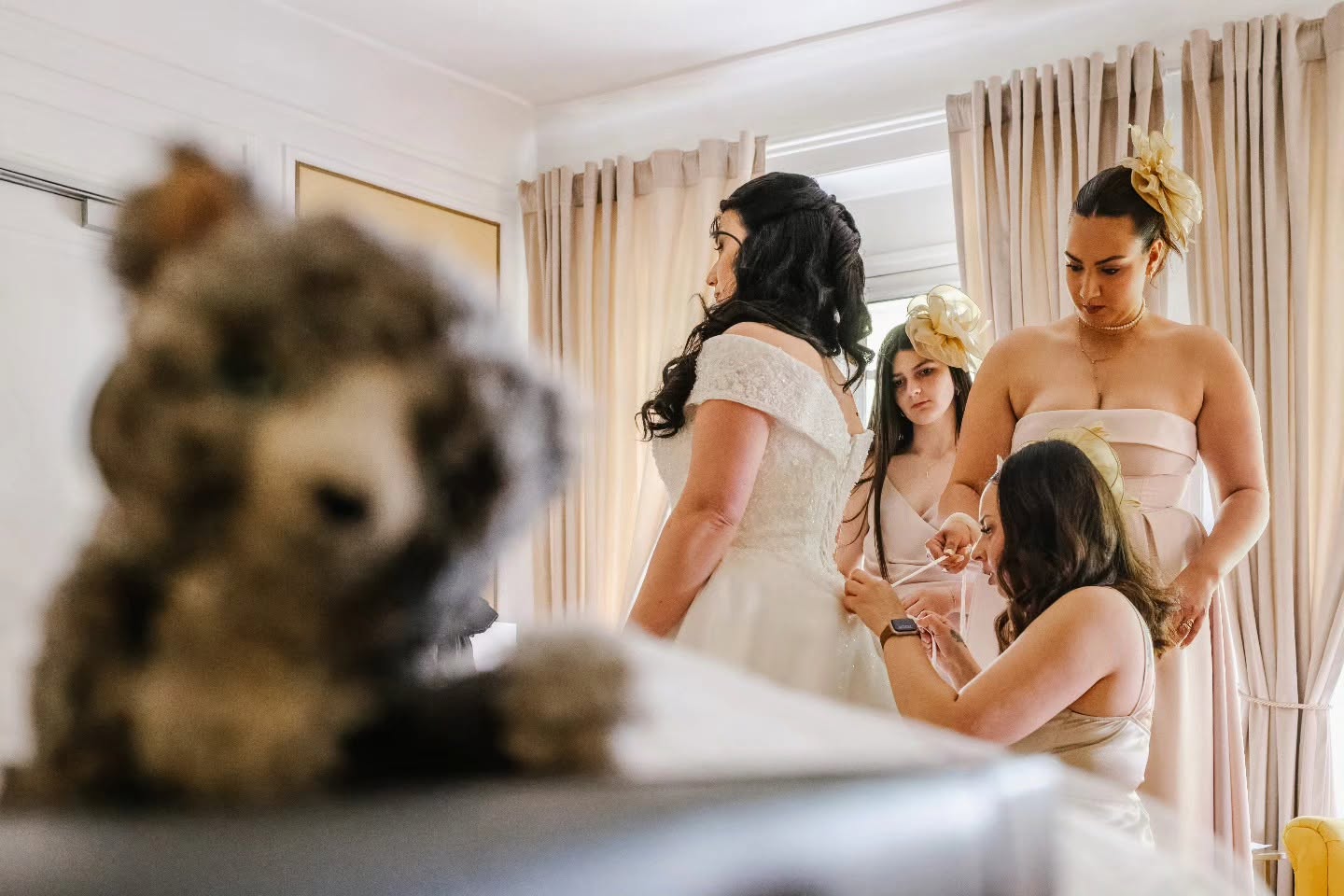 Priscillia reçoit de l’aide pour fermer sa robe de mariée dans une pièce lumineuse du château.