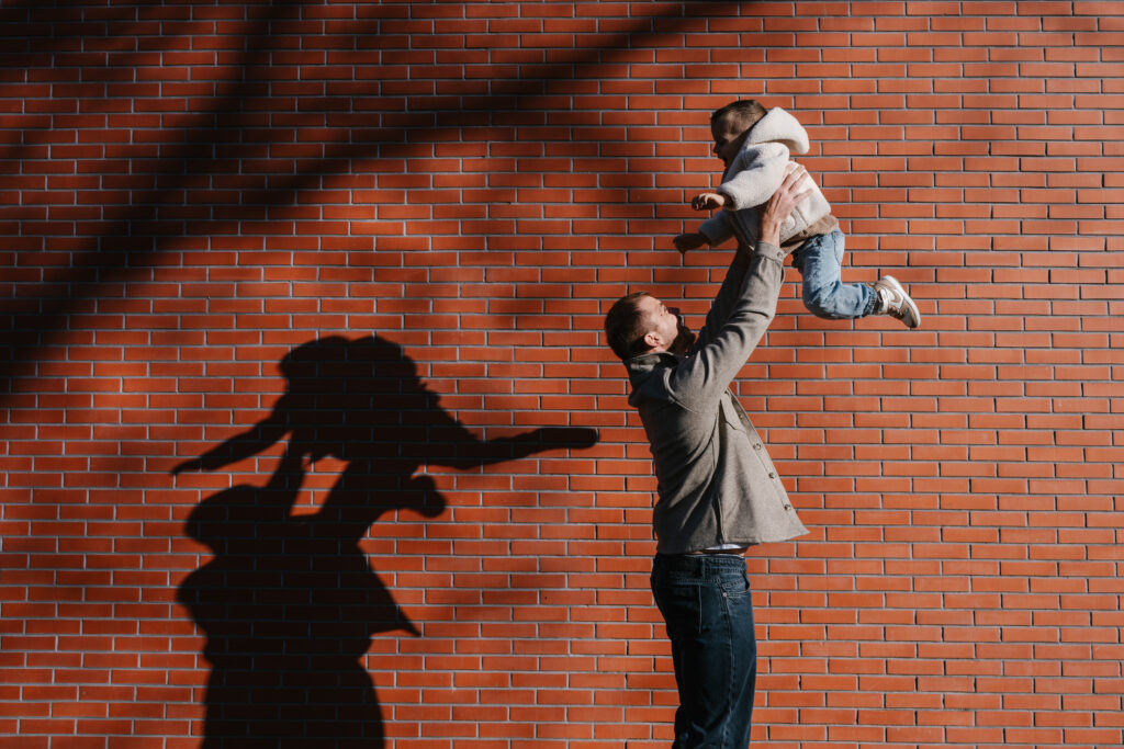Un père soulève son enfant à bout de bras pendant une séance photo en famille.