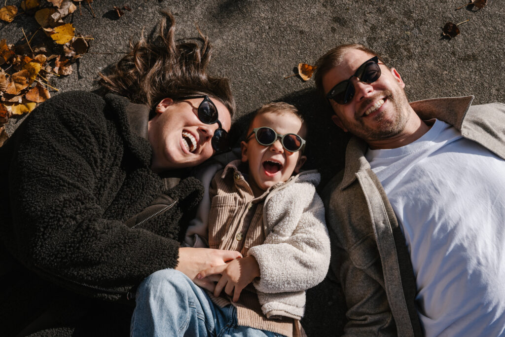 Deux parents et leur enfant rient, photographiés du dessus