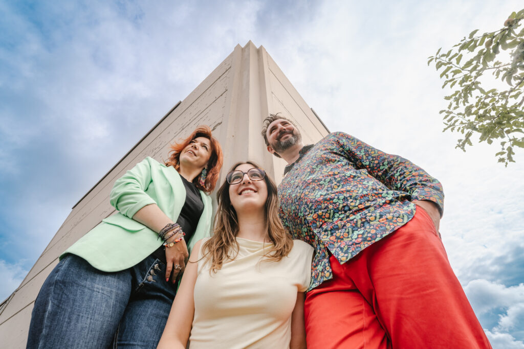 Une famille photographiée en contre-plongée, avec une veste verte, une chemise à motifs et un pantalon rouge.