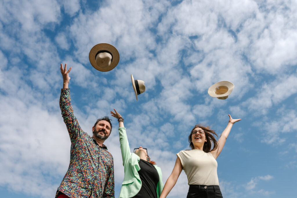 Une famille lance des chapeaux dans les airs sous un ciel nuageux.