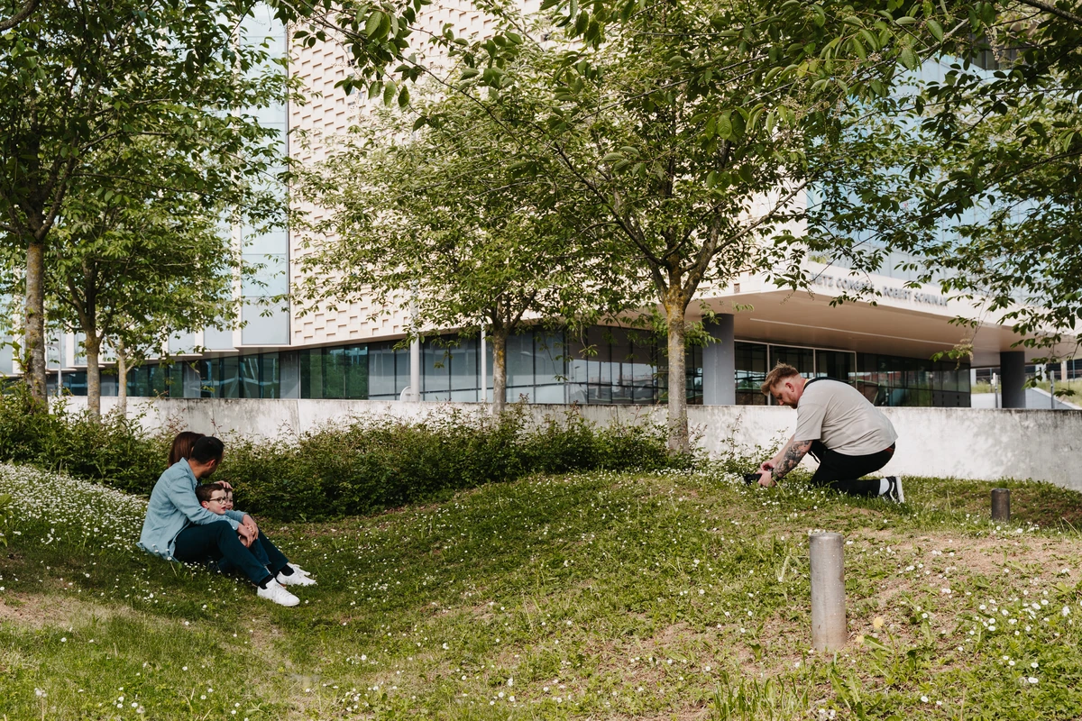 Jonathan agenouillé dans l’herbe, appareil en main, face à une famille assise