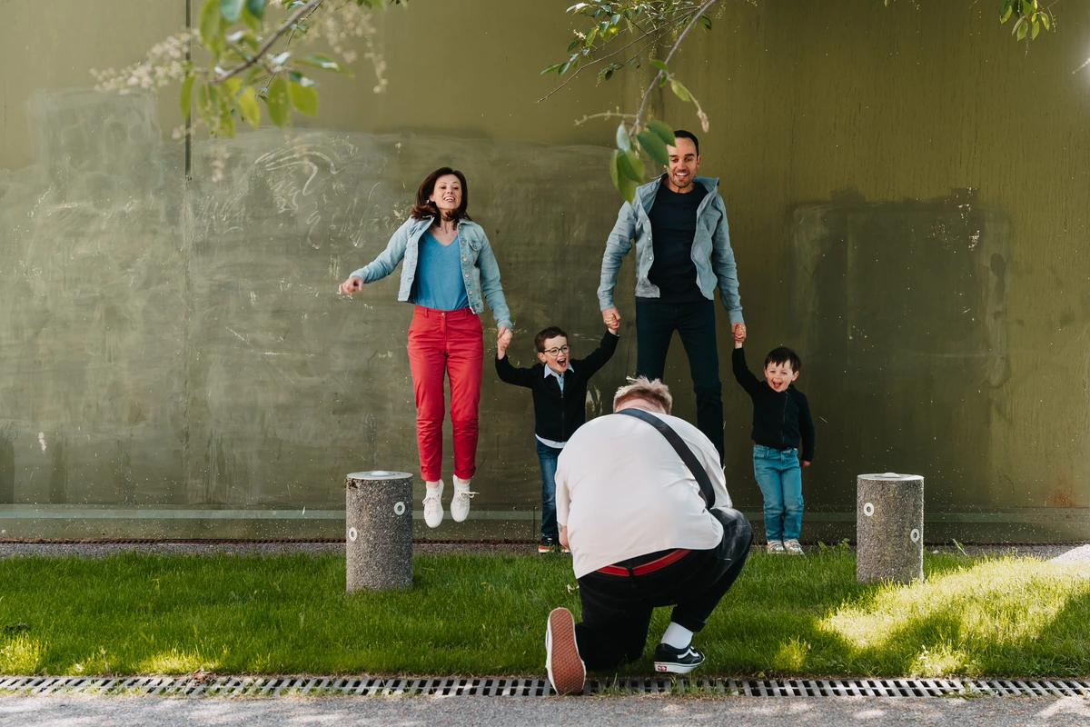 Jonathan accroupi photographie une famille qui saute en riant