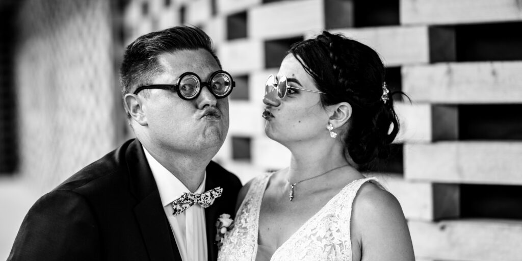 Un couple prend des poses amusantes avec des lunettes fantaisie au photobooth